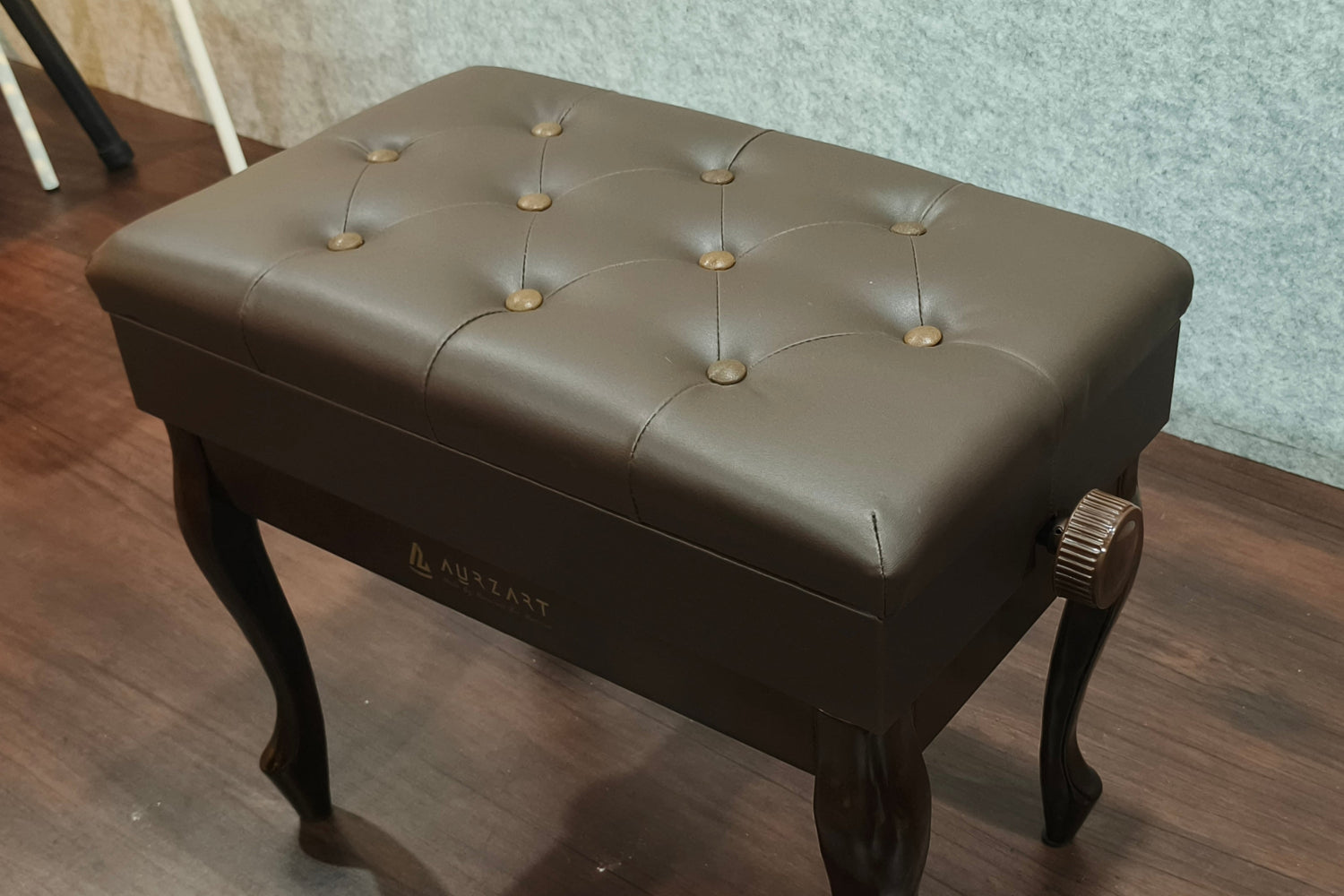 Brown leather ottoman with tufted design on a wooden floor.