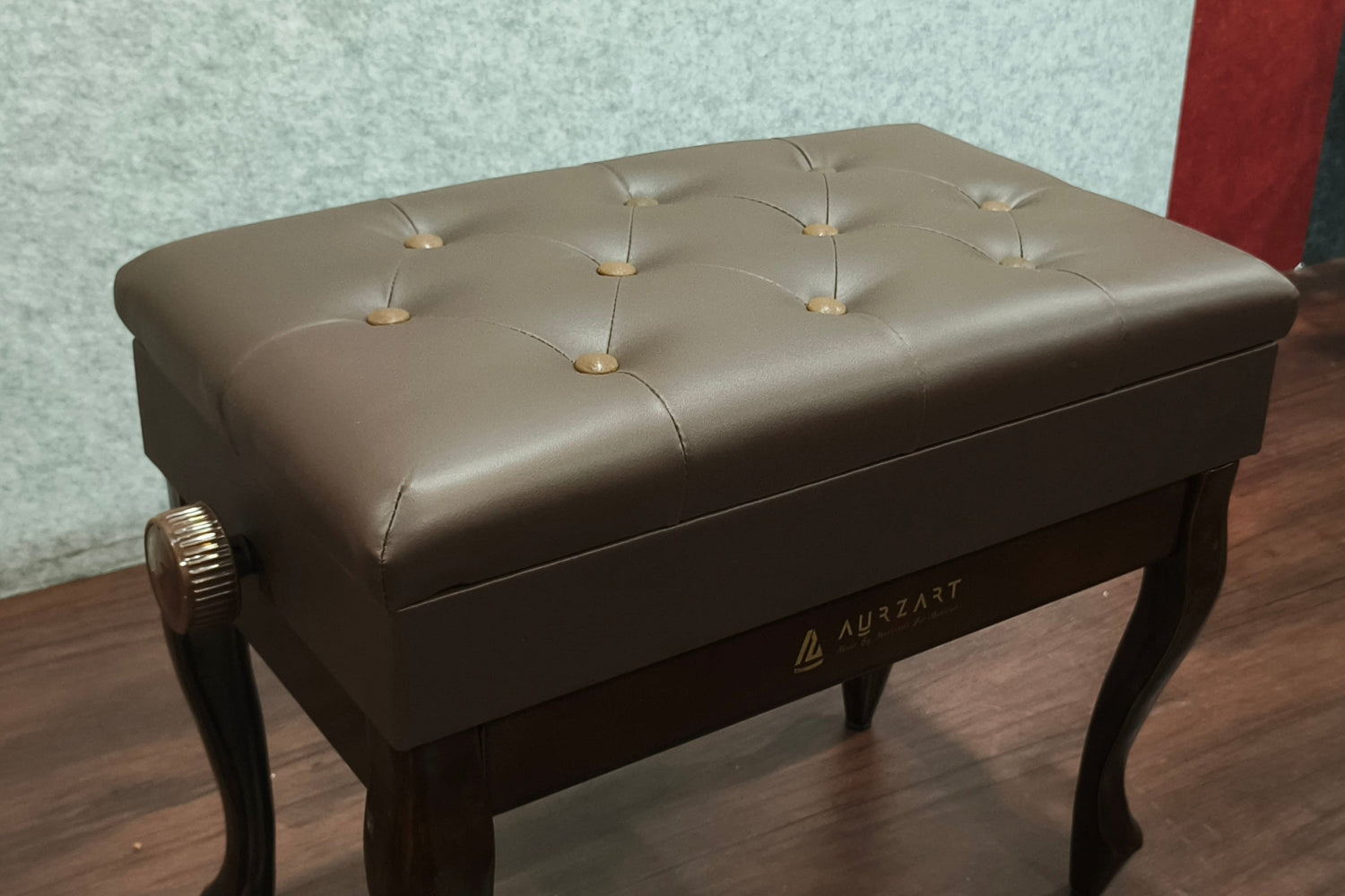 Brown leather bench with tufted design on a wooden floor.
