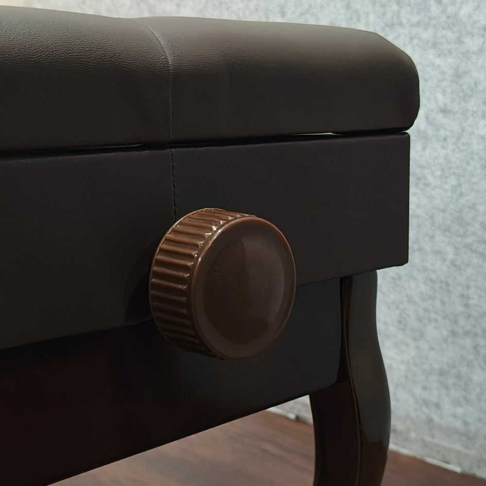 Dark brown wooden stool with a gold knob on a wooden floor.